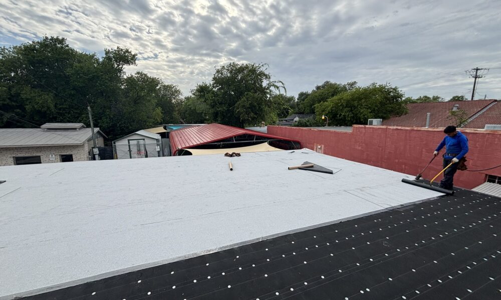 Commercial roof repair professional addressing ponding water on a flat roofing system